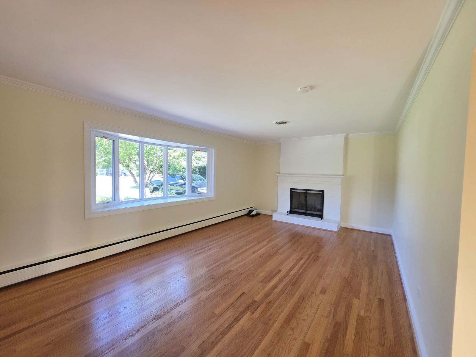 Cream-painted living room with white trim, a fireplace and refinished hardwood floors from an MGC project